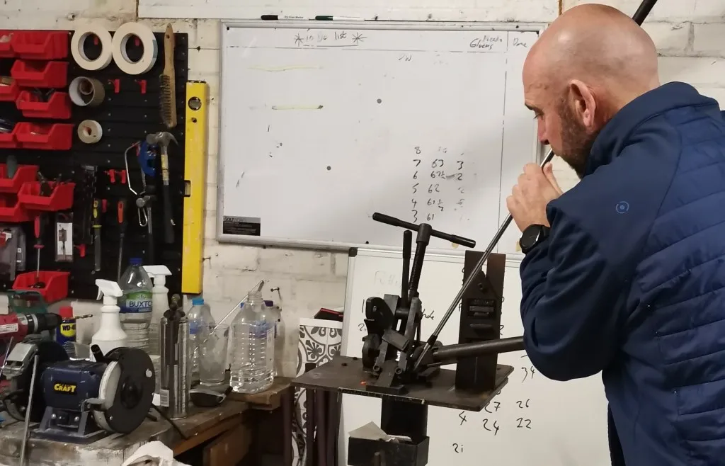 Chris working on a golf club at a workshop bench fitted with club-adjustment equipment.