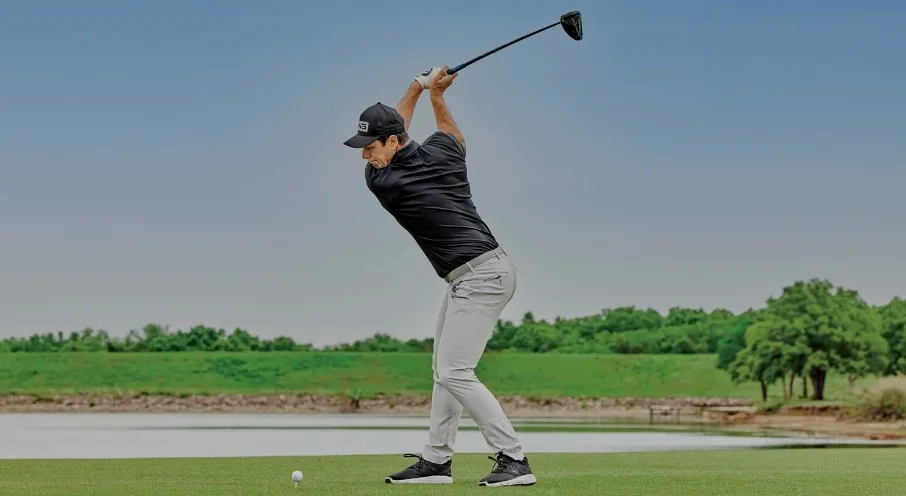 Viktor Hovland at the top of his backswing with a driver on a teeing area.